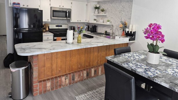 A modern kitchen with a marble countertop, stainless steel appliances, and wooden accents. - Emmanuel Midtown 2 BR 1.5 Bath Condo in Tulsa. Close to YMCA, Hospitals, Highway (Tulsa)