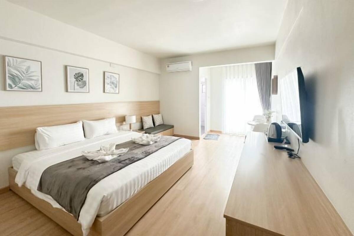 Ein modernes Hotelzimmer mit Bett, Nachttisch, Wand-Fernseher und Kunstwerk.