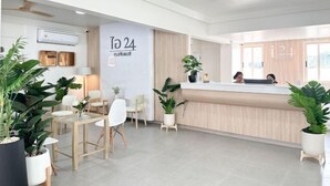 Un espace d’accueil moderne comprenant un comptoir de réception, un coin salon et des plantes en pot.