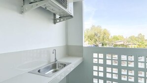 Une cuisine équipée d’un évier en acier inoxydable, d’une hotte aspirante et offrant une vue sur les arbres et les bâtiments environnants.
