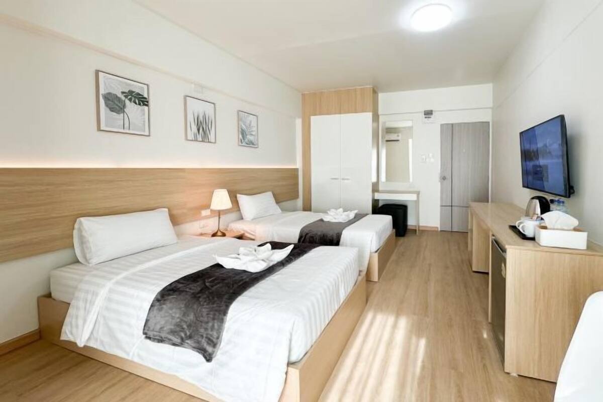 Ein Hotelzimmer mit zwei Betten, einem Schreibtisch, einem Fernseher und Bildern an der Wand.