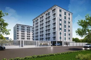 Un edificio residencial de varios pisos con un diseño moderno, con balcones y un acceso mediante portón.