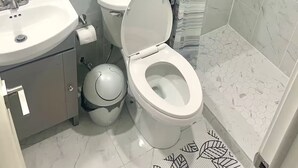 Et badeværelse med toilet, håndvask og bruser.