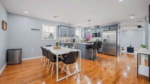 A modern kitchen with grey cabinets, stainless steel appliances, and a dining area with a white table and black chairs.