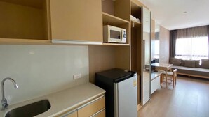 Cocina compacta con fregadero, microondas y refrigerador. Hay un comedor con mesa y sillas.