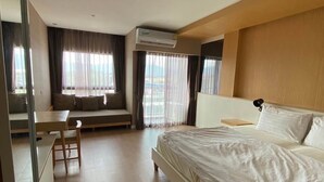 Una habitación de hotel con cama, escritorio y ventana con cortinas.