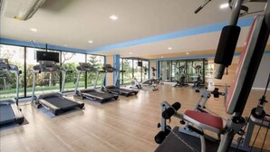 Un gimnasio con cintas de correr, elípticas y equipo de pesas.