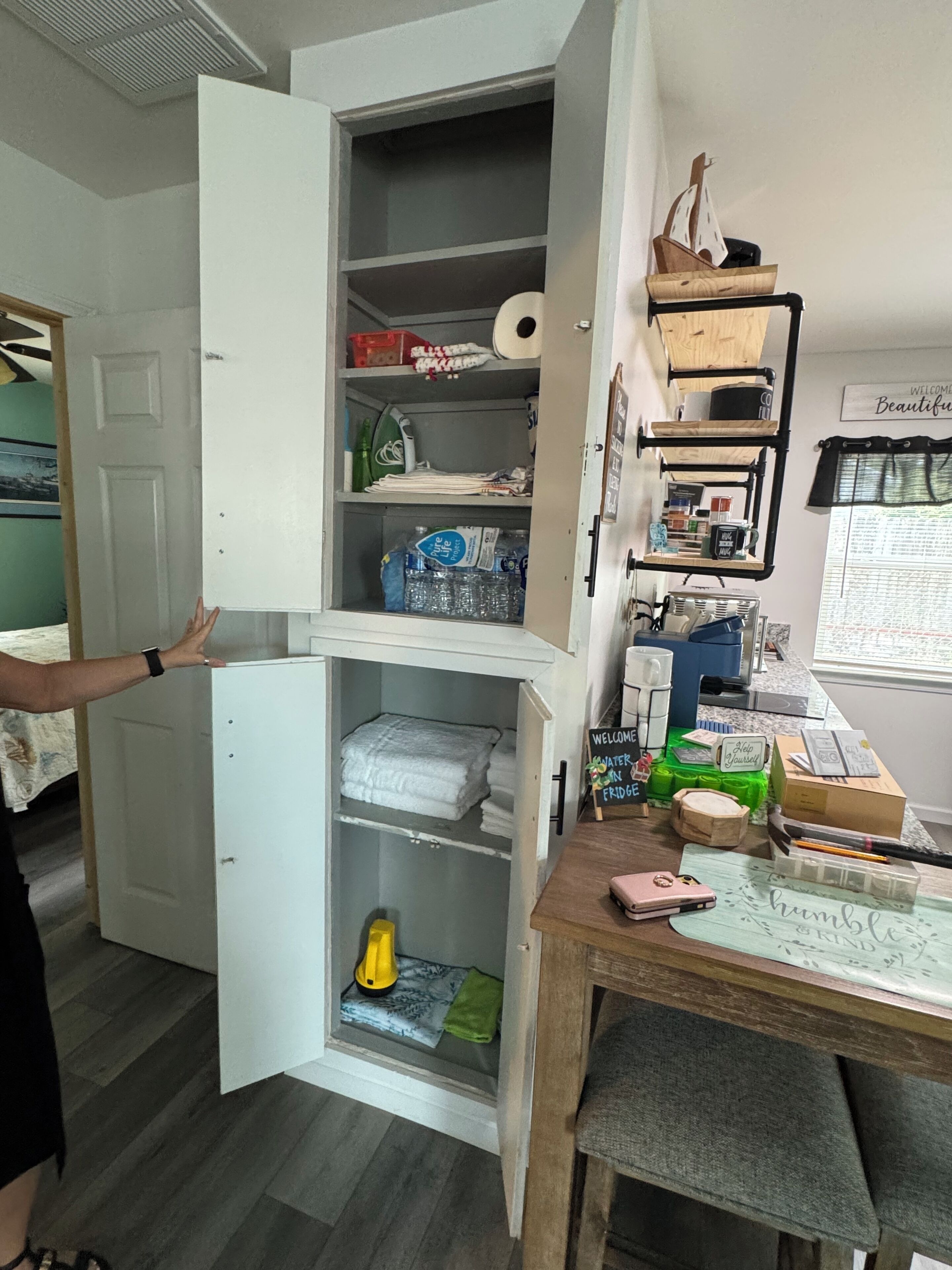 Une pièce compacte dotée d’une armoire intégrée, d’une petite table sur laquelle se trouvent divers objets, et d’une fenêtre offrant une vue agréable.