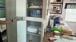A compact room with a built-in wardrobe, a small table with various items, and a window with a view.