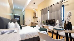 A modern hotel room with a bed, a desk, a chair, and a dining area. - EduSentral Premier Suites Setia Alam (Shah Alam)