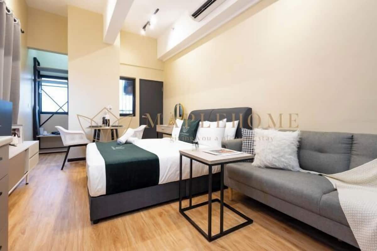 A modern hotel room with a bed, a sofa, a desk, and a chair.