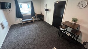 A compact room with a desk, chair, and a small table with a plant. - 248 Halls (Middlesbrough)