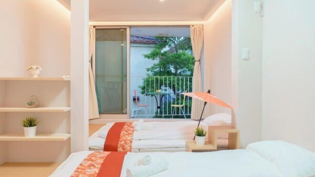 Een hotelkamer met twee bedden, een balkon met een tafel en stoelen, en uitzicht op de omgeving.