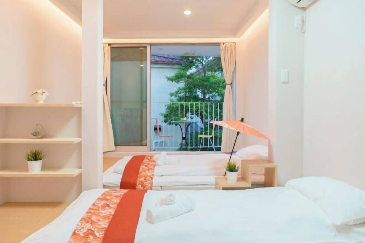 Ein Hotelzimmer mit zwei Betten, einem Balkon mit Tisch und Stühlen und Blick ins Freie.