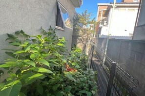 A narrow alleyway with a metal fence on one side and a building on the other. - OHAYO Hotel·Ōmorinishi (Tokyo)