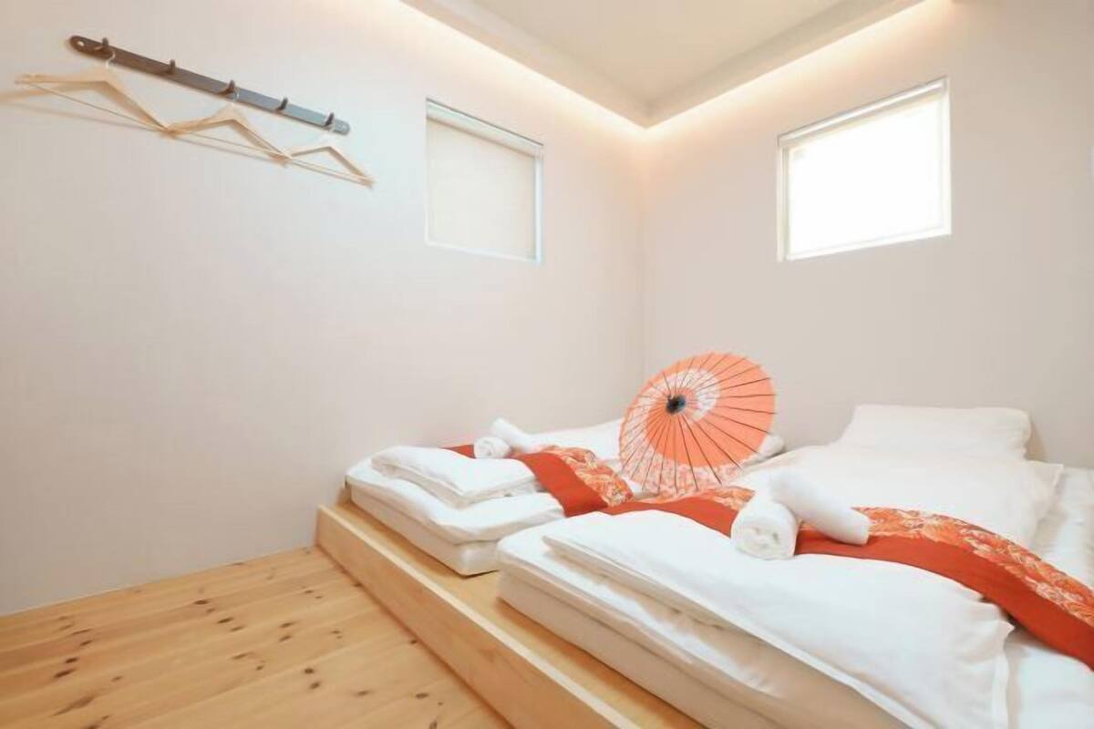 Ein Hotelzimmer mit einem Bett, einem Fenster, Holzboden und einem Handtuchhalter.