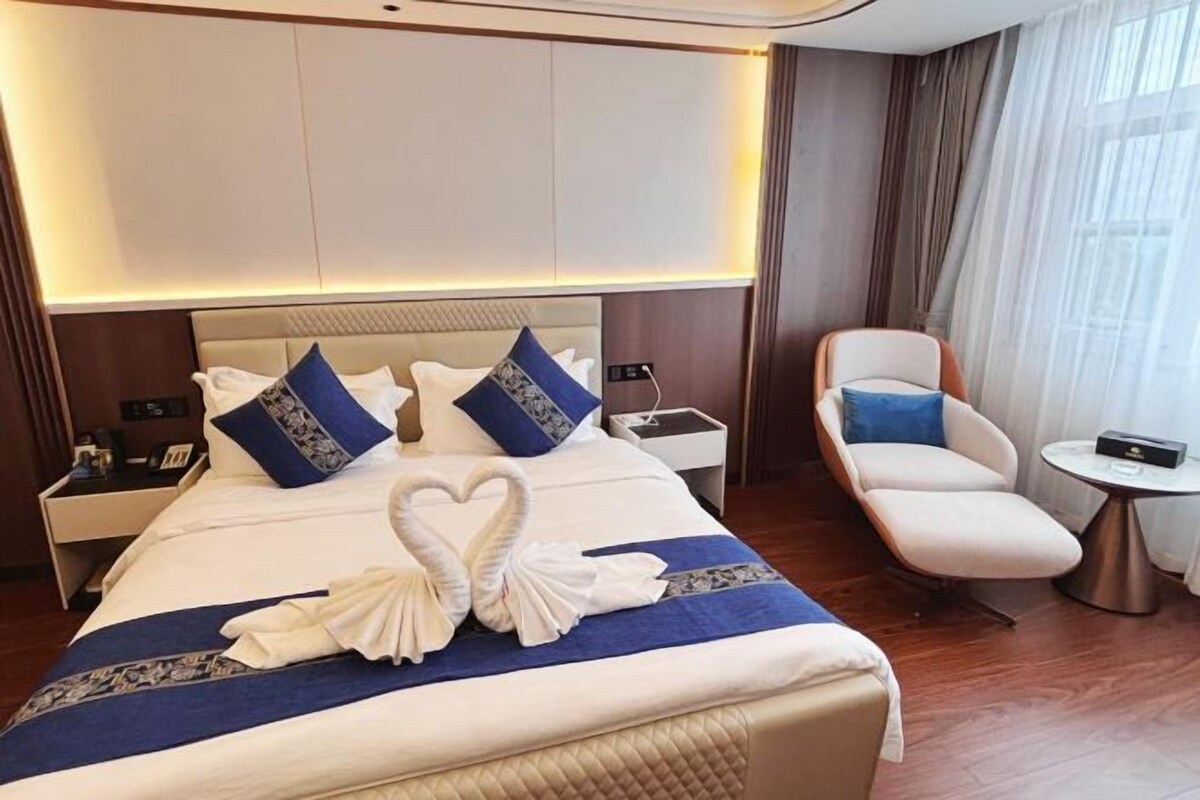 Une chambre d’hôtel avec un grand lit, une table de chevet, une chaise et une petite table.