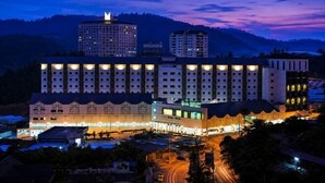 A multi-story hotel with a central courtyard, surrounded by other buildings, during nighttime. - Nova Highlands Resort & Residence (B) (Ulu Telom)
