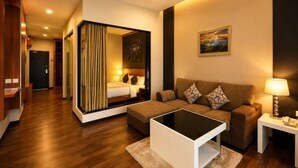 A hotel room with a sofa, a coffee table, a lamp, a painting, and a view of the hallway. - Nova Highlands Resort & Residence (B) (Ulu Telom)