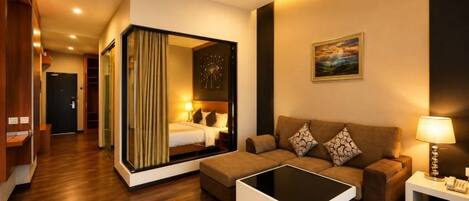 A hotel room with a sofa, a coffee table, a lamp, a painting, and a mirror.