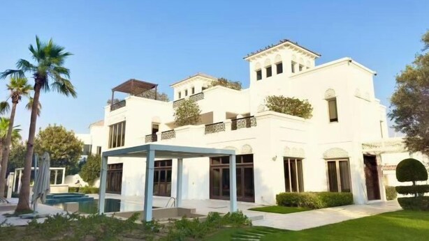 Um edifício branco de vários andares com varandas, área de estar coberta ao ar livre e uma piscina.