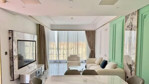 Uma sala de estar moderna com uma televisão grande, uma mesa de jantar e um sofá.