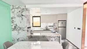 Uma cozinha moderna com bancadas de mármore, forno embutido e geladeira de aço inoxidável.