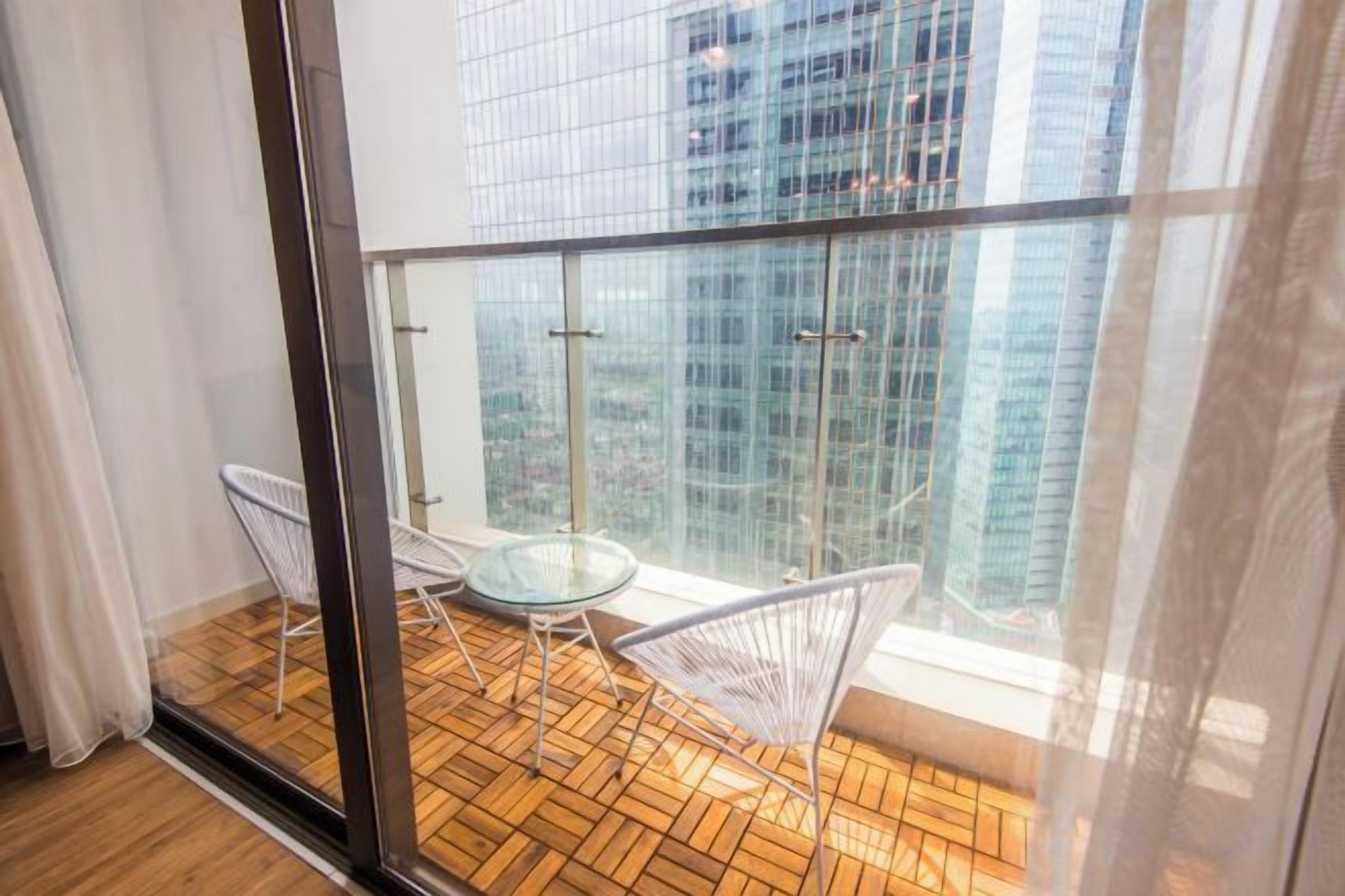 A balcony with a glass door, two chairs, and a small table.