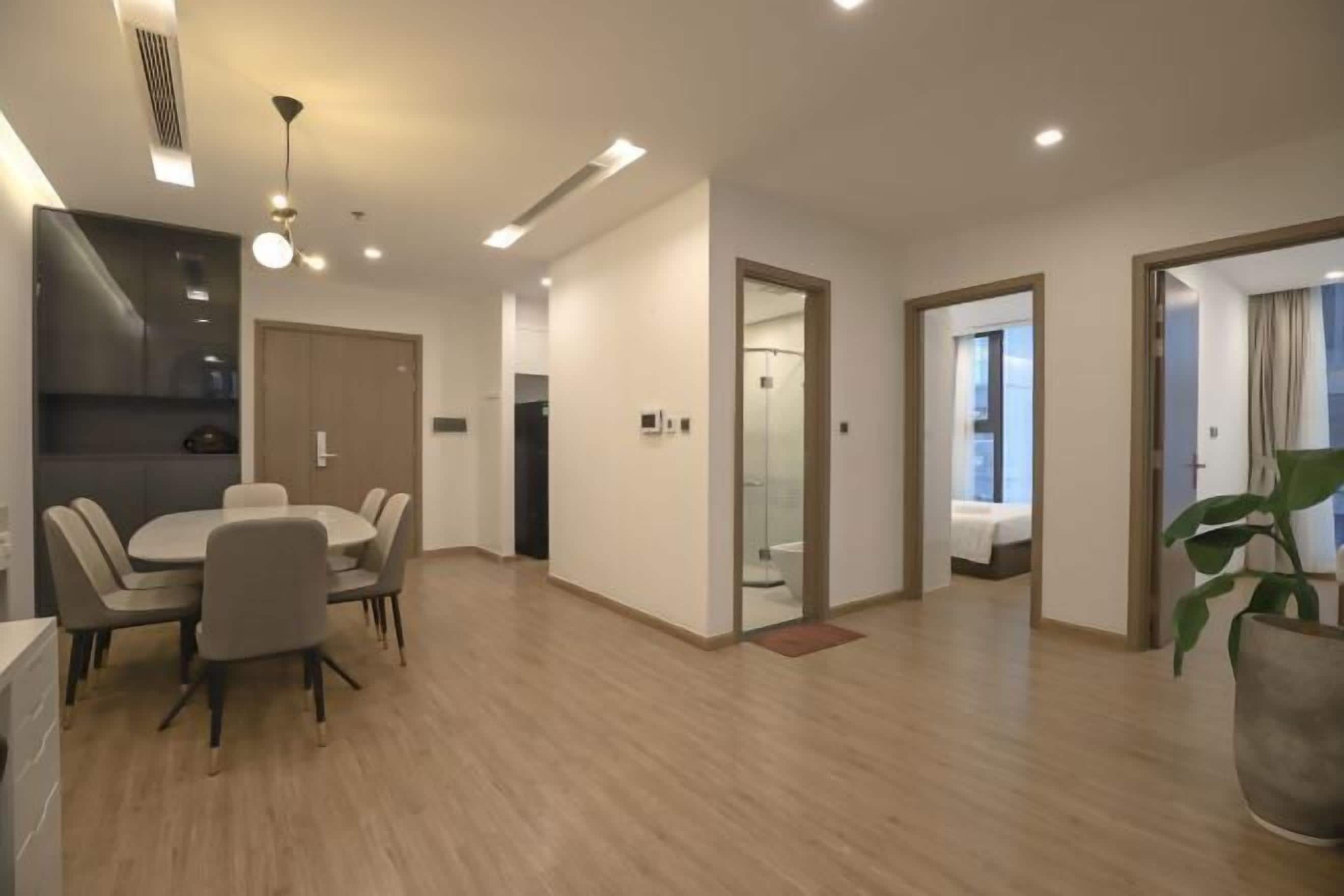 A modern hotel room with a dining area, a kitchen, and a bathroom.
