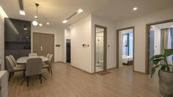 A modern hotel room with a dining area, a kitchen, and a bathroom.