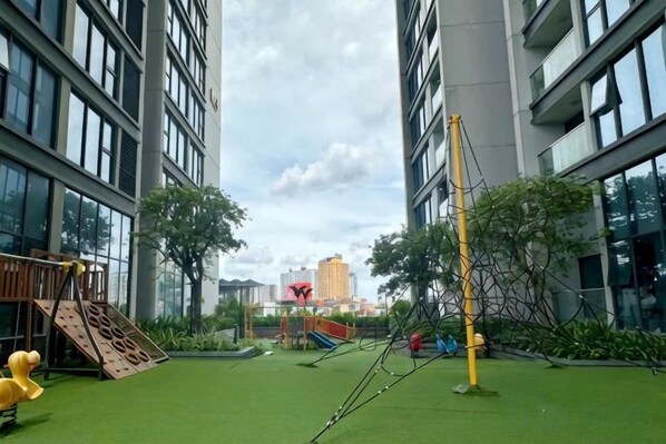 A playground with climbing structures and a slide, surrounded by greenery and buildings. - Vinhomes Metropolis Apartment - Comfort Stay Ha Noi (Hanoi)