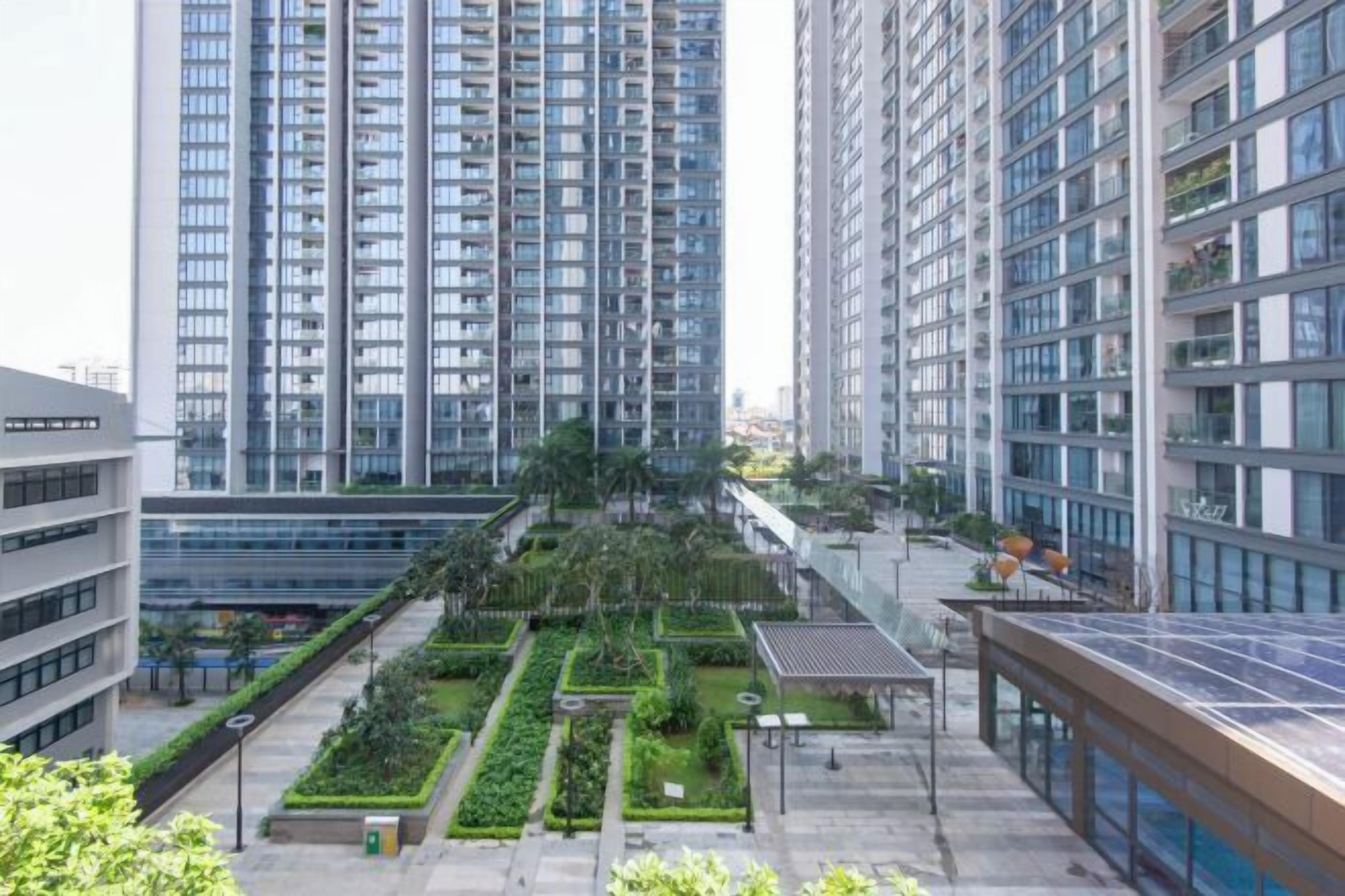 A modern high-rise building with multiple floors, a rooftop garden, and a solar panel array.
