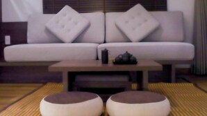 A modern living room with a sofa, ottomans, and a small table with a teapot. - KATOYA SUITES SAIGON HONKAN (Ho Chi Minh City)