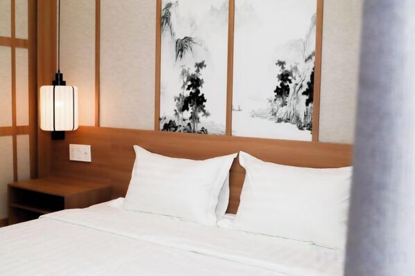 A hotel room with a bed, a nightstand, and a wall-mounted lamp.
