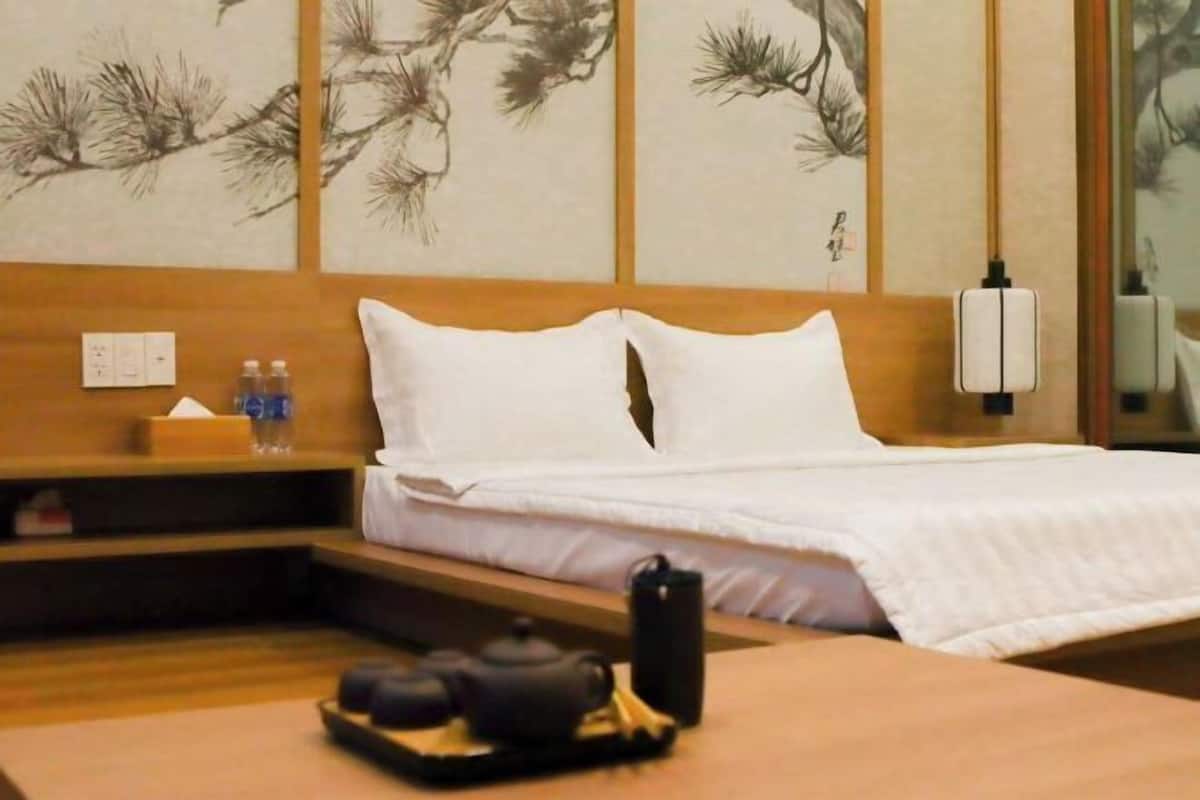 Ein Hotelzimmer mit Bett, Nachttisch und einer Wand mit Kunstwerken.