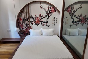 A bedroom with a bed, pillows, a wooden floor, a wall-mounted shelf, and a mirror. - KATOYA SUITES SAIGON HONKAN (Ho Chi Minh City)