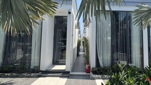 Un bâtiment moderne doté de grandes fenêtres en verre, d’une entrée centrale et d’un chemin menant à l’entrée principale.
