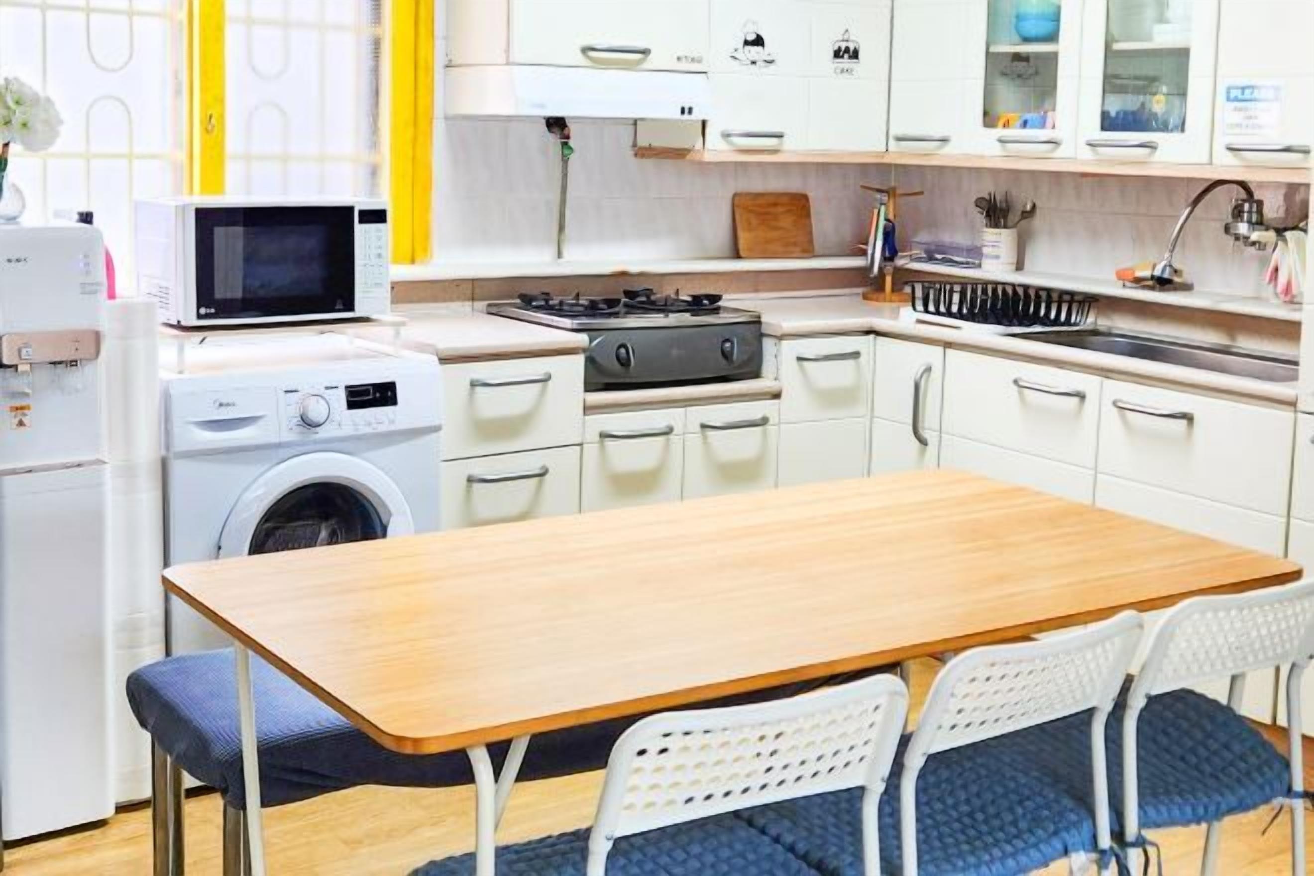 Une cuisine compacte équipée d’un four à micro-ondes, d’un lave-linge et d’une cuisinière à gaz.