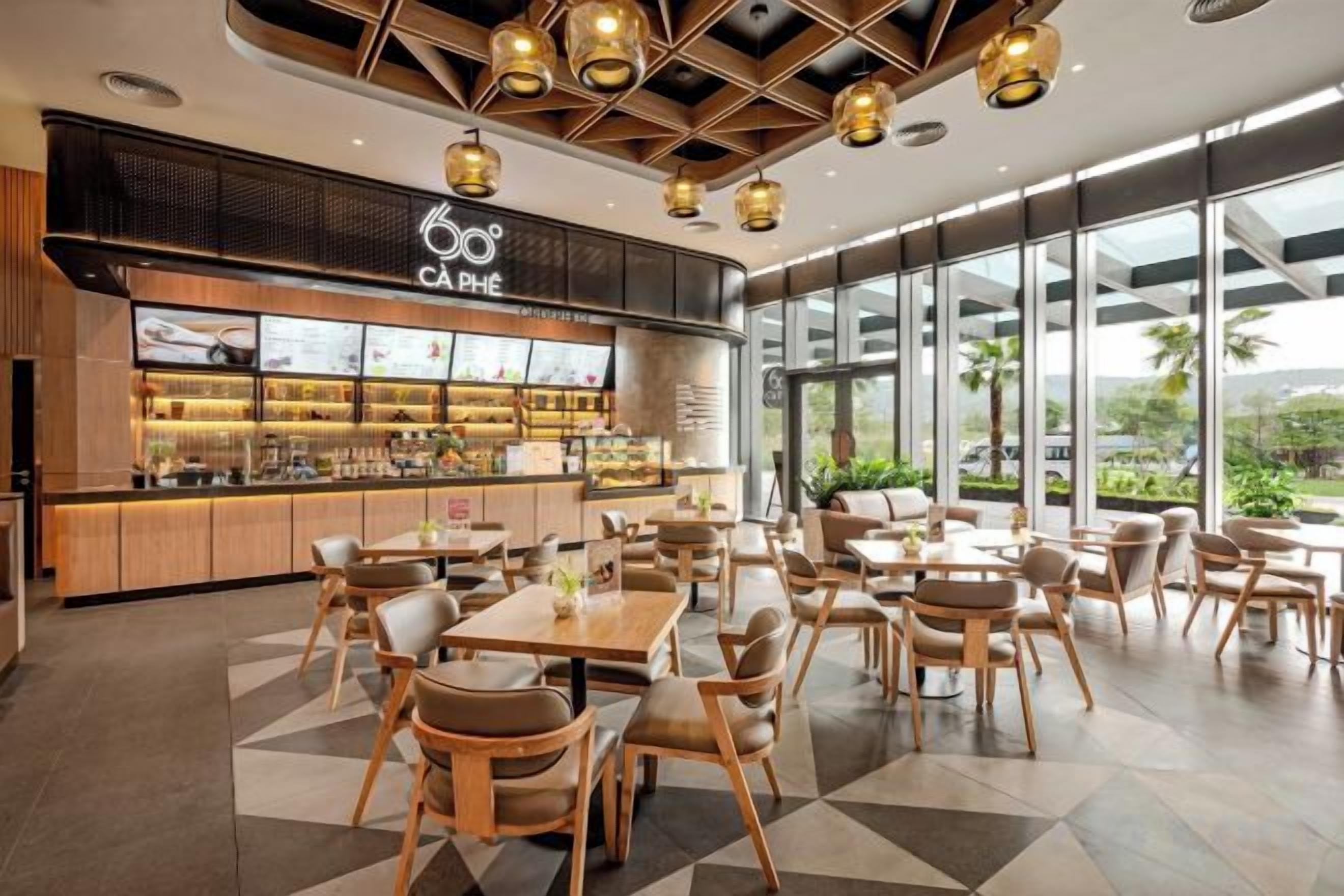 Ein Café mit modernem Interieur, inklusive einer Theke mit einer Auslage, verschiedenen Sitzbereichen und großen Fenstern mit Blick.