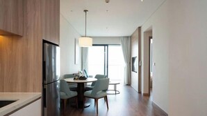 A modern hotel room with a dining area, a large window, and a flat-screen TV. - Alacarte Ha Long - Service Apartment (Ha Long)