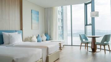 Ein Hotelzimmer mit zwei Betten, einem Esstisch und Blick auf die Stadt.