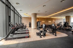 A modern gym with treadmills, weight machines, and a large mirror. - Alacarte Ha Long - Service Apartment (Ha Long)