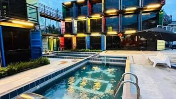 A swimming pool with a metal ladder, surrounded by a poolside area with lounge chairs.