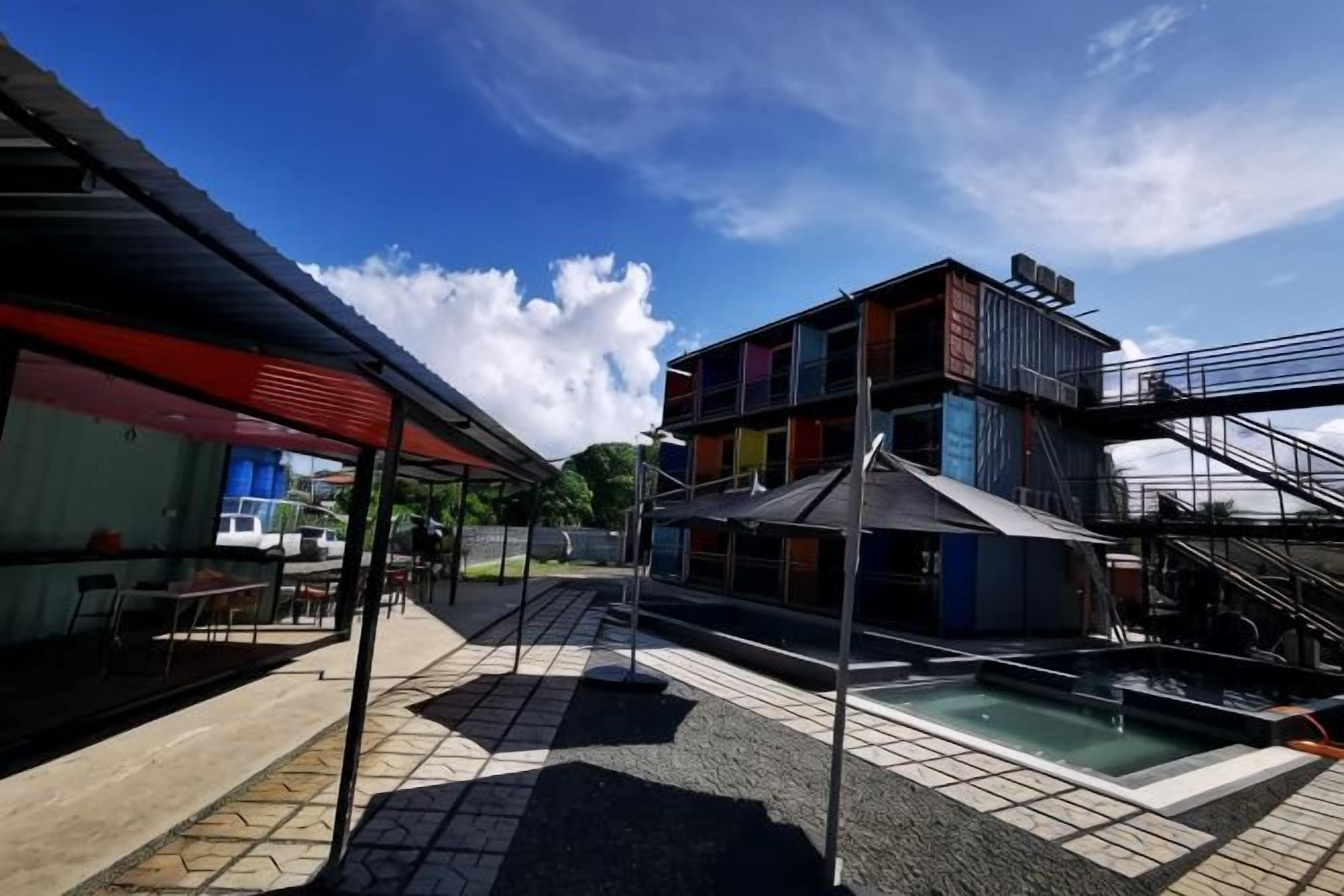 A covered outdoor area with a pool, a staircase, and a building with multiple floors and colorful facades.