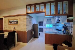 A kitchen with a built-in island, wooden cabinets, and a dining area with chairs. - Jacuzzi Pool Villa (Pattaya)