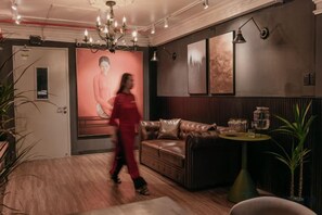 A modern interior with a leather sofa, a round table, and a chandelier. - MG Rosé Boutique Hotel - Saigon City Lights (Ho Chi Minh City)
