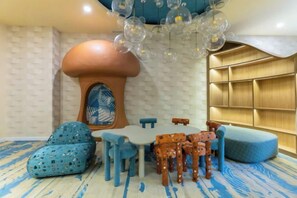 Une pièce dotée d’une cheminée originale en forme de champignon, d’une table ronde et de chaises à motifs bleus.