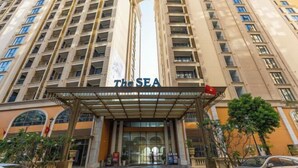Un hotel de varios pisos con una entrada destacada, balcones y un letrero que dice 'The SEA'.