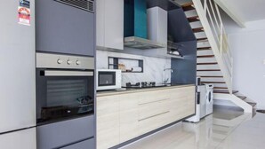 A modern kitchen with a built-in oven, microwave, and a wooden countertop.