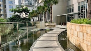 A modern building with a water feature, glass railings, and greenery. - Super Cozy and Clean Apartment connected to mall (West Jakarta)